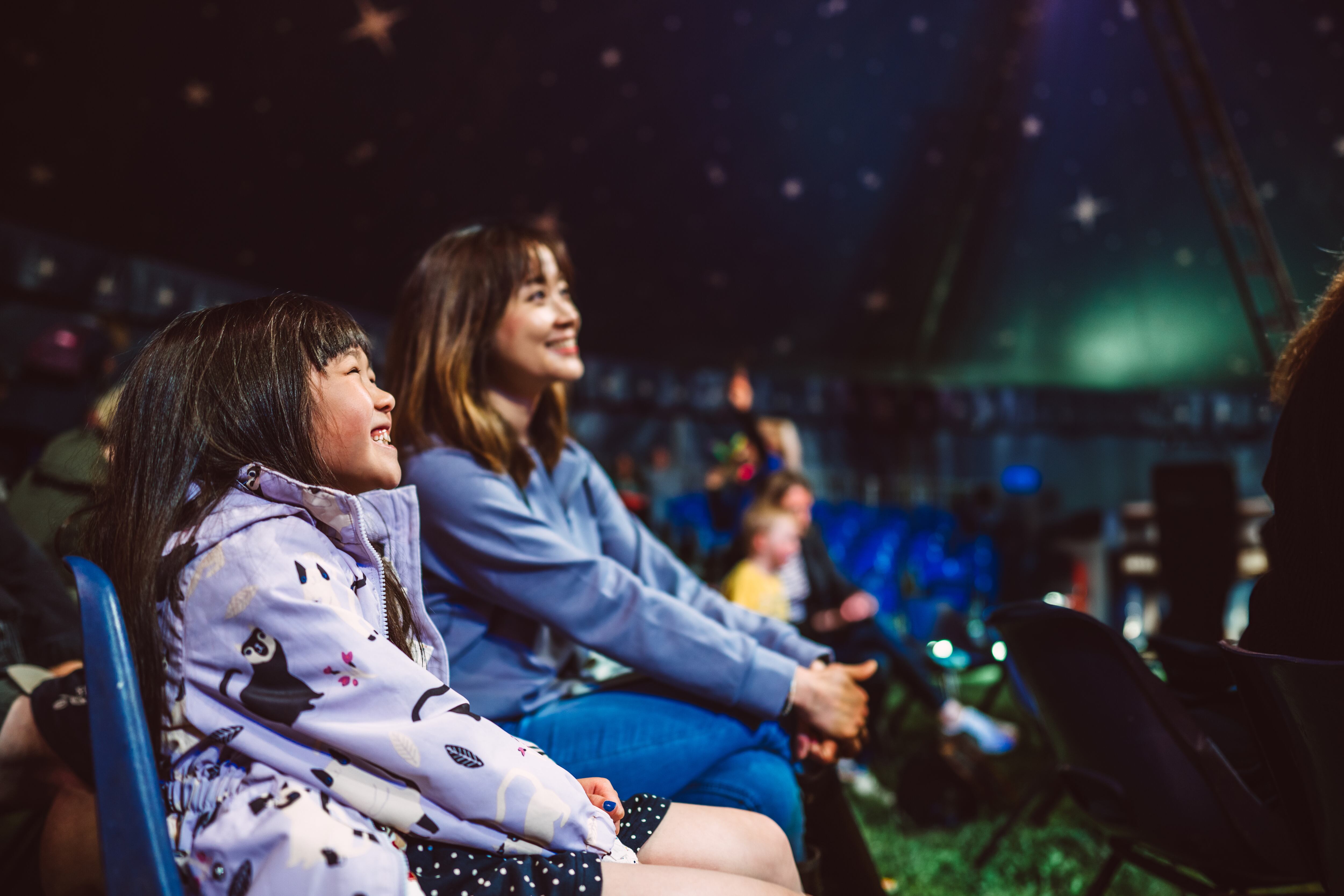 Madre disfrutando un espectáculo de circo junto con su hija