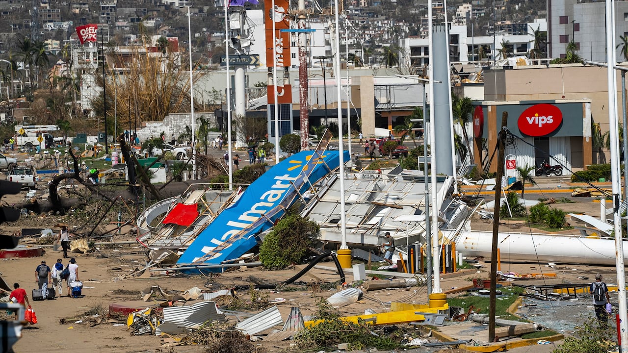 Residentes caminan entre los escombros que dejó el paso del devastador huracán Otis, de categoría 5, en Acapulco, México, el viernes 27 de octubre de 2023. (AP Foto/Félix Márquez)