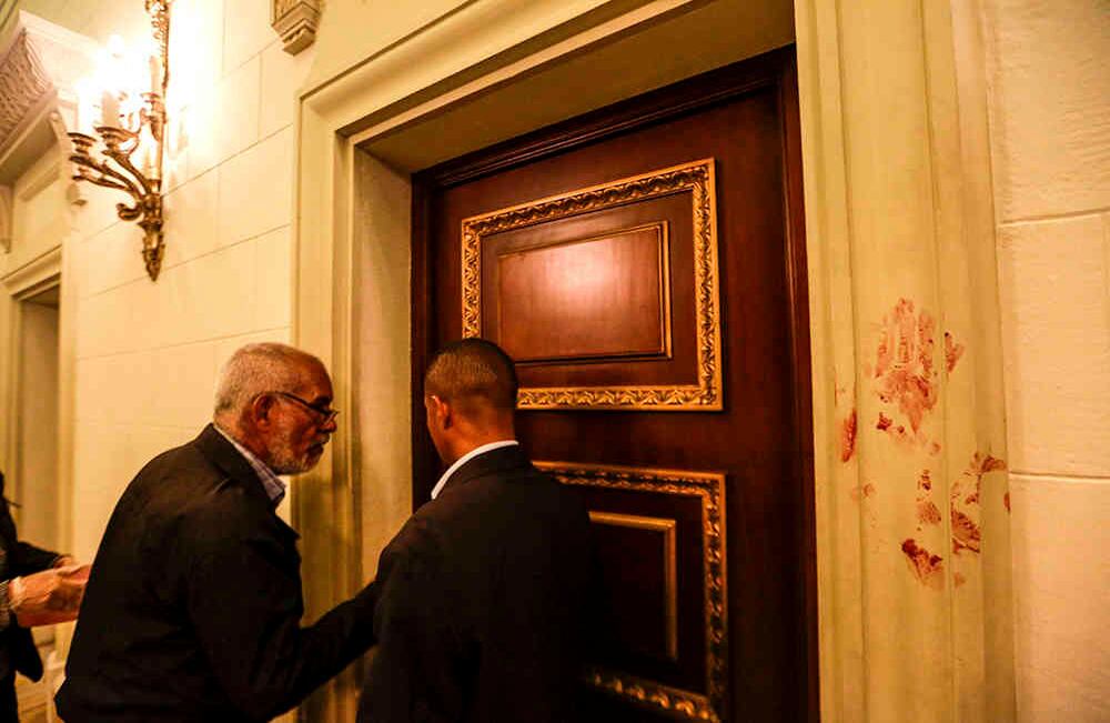 Hombres conversan junto a una pared manchada de sangre en la sede de la Asamblea Nacional hoy, miércoles 5 de julio de 2017, en Caracas, Venezuela. Un grupo de simpatizantes del chavismo, con palos y armas de fuego, se tomó los accesos del lugar e ingresó a la fuerza dejando a varios diputados y asistentes heridos. EFE/CRISTIAN HERNÁNDEZ