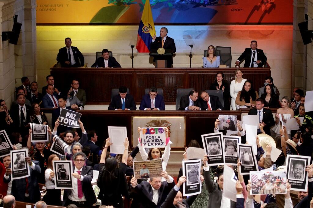 El presidente de Colombia, Iván Duque, habla durante la instalación del Congreso 2022-2026 en Bogotá, el 20 de julio de 2022. Al frente suyo, la oposición con pancartas