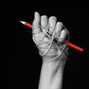 Hand with red pencil tied with rope, depicting the idea of freedom of the press or freedom of expression on dark background in low key. international human rights day concept.