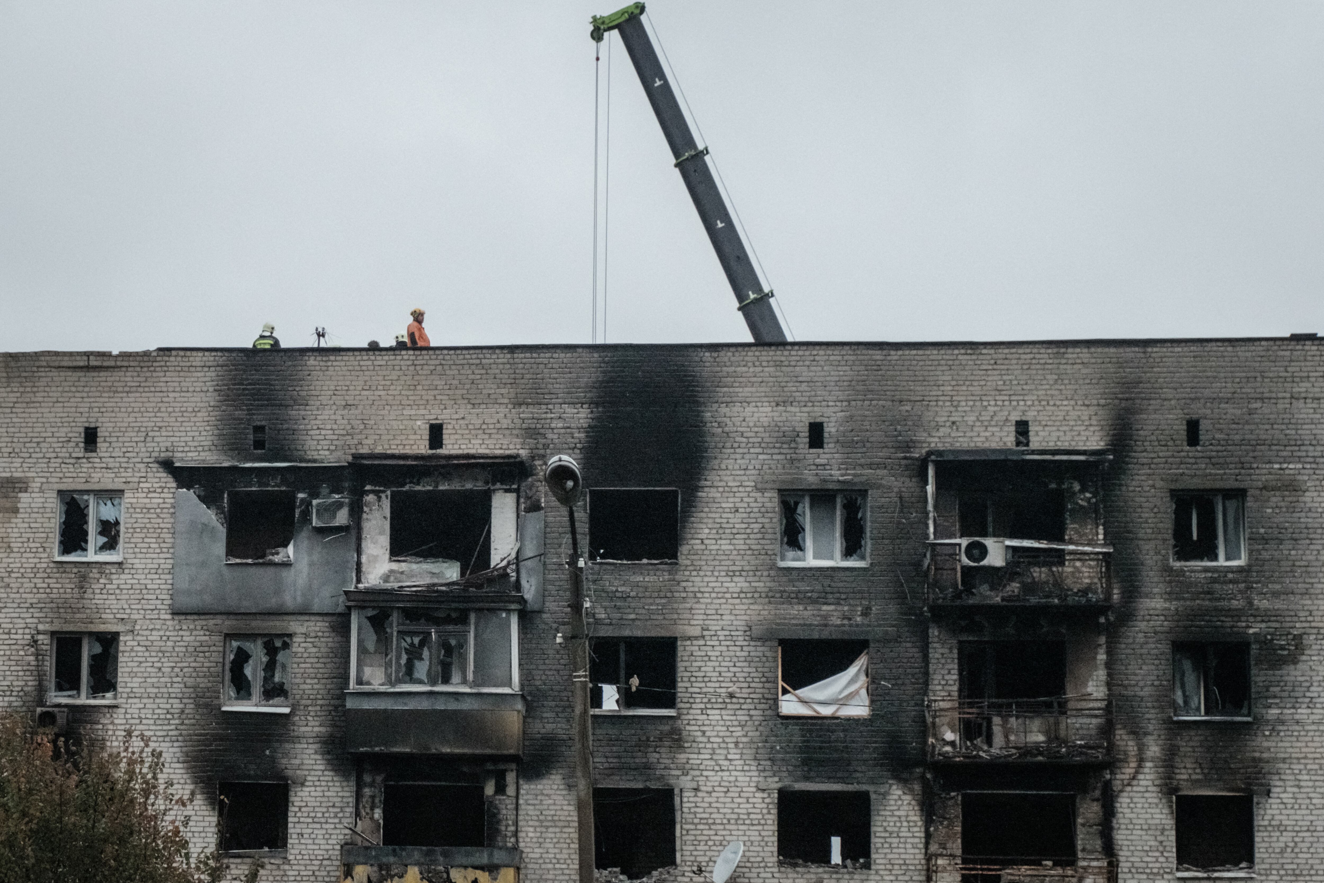Los trabajadores reparan la parte superior de un apartamento quemado en la ciudad recientemente recuperada de Izyum, en la región de Donetsk, el 10 de octubre de 2022, en medio de la invasión rusa de Ucrania. (Foto de Yasuyoshi CHIBA / AFP)