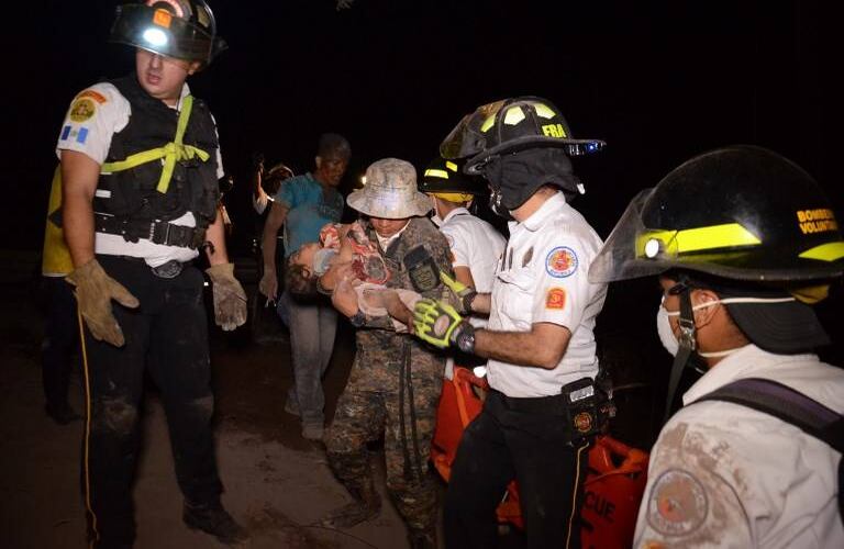 Un bombero voluntario carga a un niño después de la erupción del volcán Fuego, en el pueblo de El Rodeo departamento de Escuintla a 35 km al sur de Ciudad de Guatemala. Noe Pérez / AFP