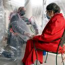 Gregg MacDonald toma de la mano a su madre de 84 años, Chloe MacDonald, en una "carpa de abrazos" instalada fuera del centro de vida asistida de Juniper Village en Louisville, Colorado, el miércoles 3 de febrero de 2021. La carpa incluye una construcción -Barrera de plástico de grado con fundas de plástico incorporadas para evitar la propagación del coronavirus. (Foto AP / Thomas Peipert)