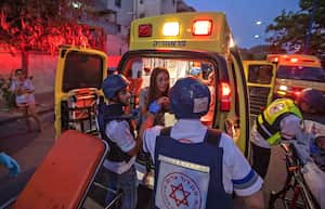 Rescue workers evacuate a woman by ambulance, amidst a rocket attack from the Gaza Strip, in the southern Israeli city of Sderot, on May 12, 2021. - Gaza militants have launched more than 1,000 rockets since the beginning of this week according to Israel's army, which has carried out hundreds of air strikes in the crowded coastal enclave of Gaza. (Photo by Yehuda Perez / AFP) / Israel OUT