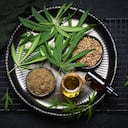 Marijuana plant with cannabis oil, cannabis protein and cannabis seeds in a big black bowl on a black background. Top view.