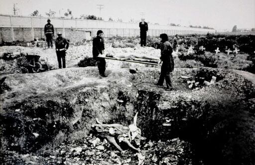 Esta fotografía fue tomada el 22 de enero de 1986 a las 8 de la mañana en el Cementerio Sur de Bogotá. 
Se observa un hueco y en el fondo de este se pueden ver varios cuerpos que han sido arrojados. Dos hombres, vestidos con batas, se preparan para arrojar otro cadáver. A la izquierda se ven dos funcionarios del cementerio que observan la macabra escena. Al fondo de la imagen, parado sobre un montículo, se ve un misterioso hombre vestido de traje y con un sombrero, que parece supervisar lo que está ocurriendo. Curiosamente, en los archivos no hay registros oficiales sobre inhumaciones realizadas el 22 ó 23 de enero de 1986 en alguno de los cementerios de Bogotá. La actividad que está registrada en esta foto no contaba con el permiso de autoridades como Medicina Legal