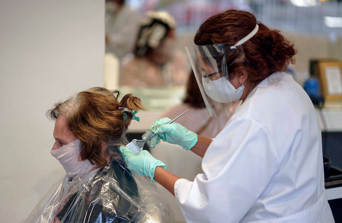 Una esteticista que usa una máscara facial como precaución contra la propagación del nuevo coronavirus trabaja en un cliente en un salón de belleza en Montevideo, Uruguay. (Foto AP / Matilde Campodonico)