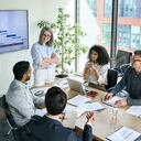 Directora ejecutiva senior y empresarios multiculturales discutiendo la presentación de la empresa en la mesa de juntas. Diverso equipo corporativo trabajando juntos en la moderna oficina de la sala de reuniones. Vista superior a través del vidrio