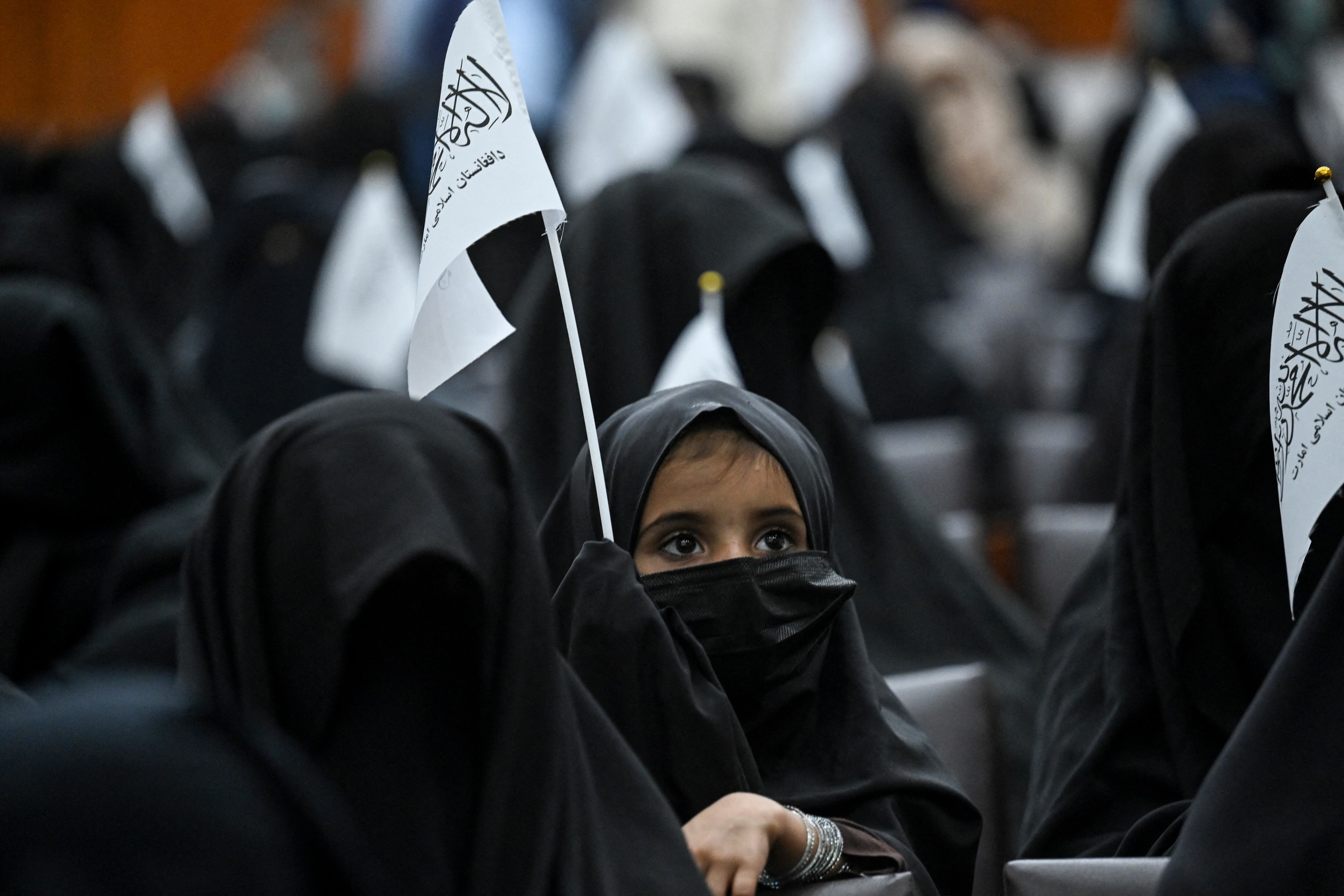 Una niña con velo sostiene una bandera de los talibanes durante una reunión de mujeres aturdidas antes de una manifestación a favor de los talibanes en la Universidad de Educación Shaheed Rabbani en Kabul el 11 de septiembre de 2021 (Foto de Aamir QURESHI / AFP).
