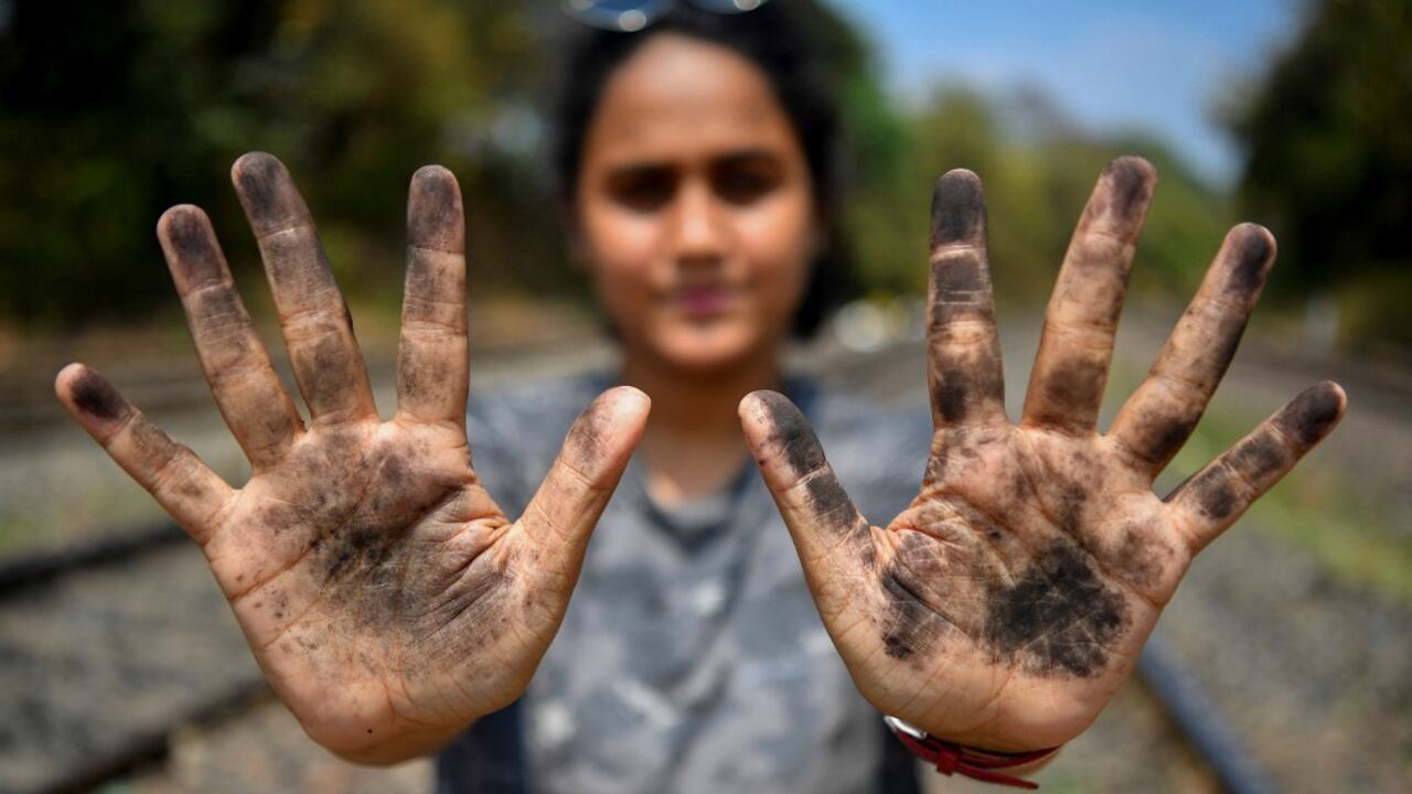 En esta fotografía tomada el 11 de marzo de 2021, la zoóloga Hycintha Aguiar muestra sus manos cubiertas de hollín tras manipular el carbón caído a las vías del tren de carga en la estación de tren de Kulem, en Goa. Foto de Indranil Mukherjee / AFP