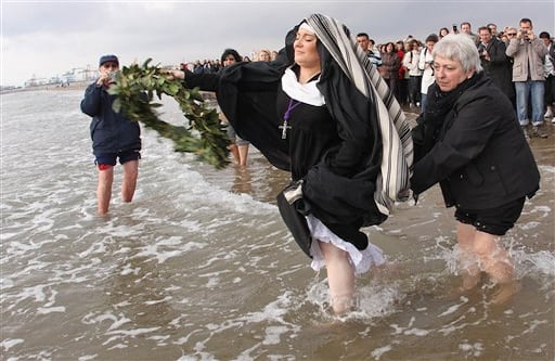 (Valencia, España) Una mujer penitente del Santísimo Cristo Salvador lanza una ofrenda florar durante la procesión de este viernes en la playa de Valencia. (AP Photo/Alberto Saiz) 
