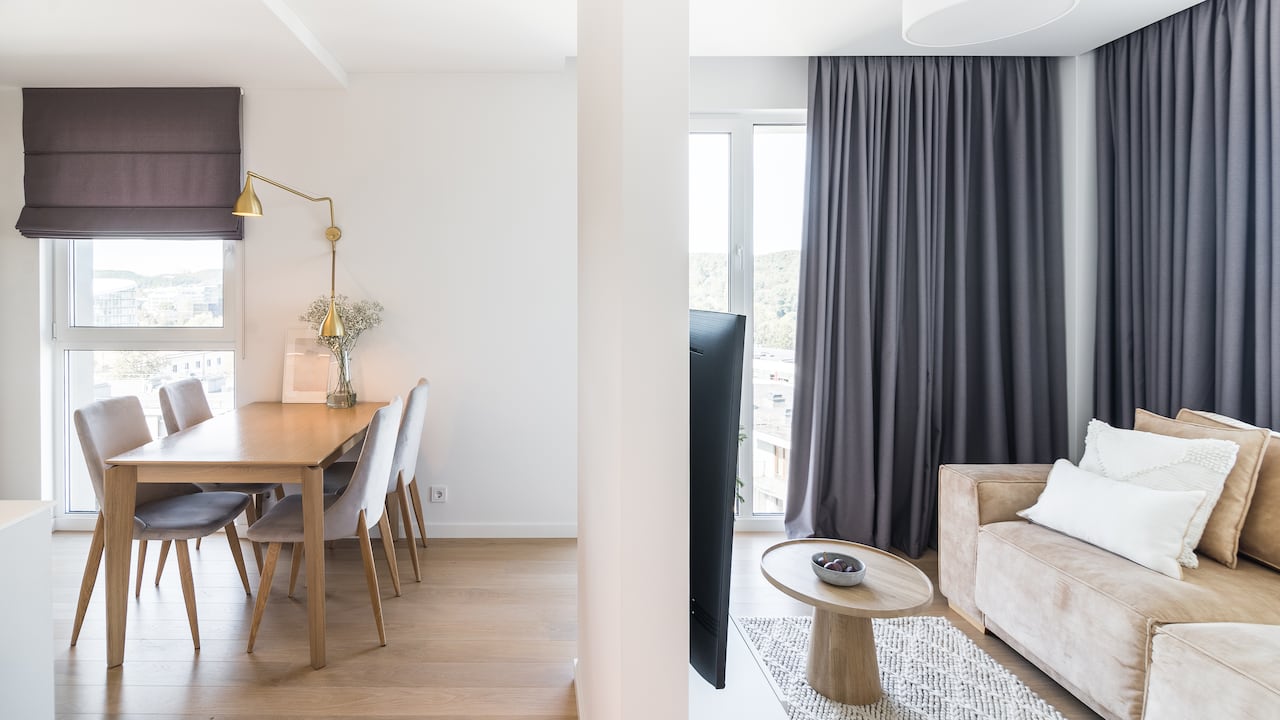 Apartamento nuevo y moderno con un comedor y salas de estar separados por la pared.