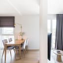 Apartamento nuevo y moderno con un comedor y salas de estar separados por la pared.