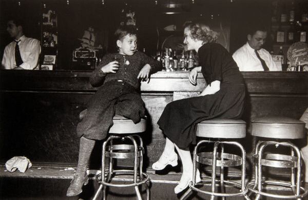 Ciudad Calumet, Illinois, Estados Unidos. Diciembre de 1940. Los sabados en la noche los trabajadores de ciudades cercanas llegaban a Calumet buscando divertirse en los bares de la ciudad. Al área se le conocía como “la ciudad del pecado”. Esta foto la publicó la revista Life y hubo un escándalo por el niño que aparece bebiendo en la barra de un local. La revista luego aclaró que se trataba del hijo del dueño y que no estaba bebiendo alcohol sino gaseosa.