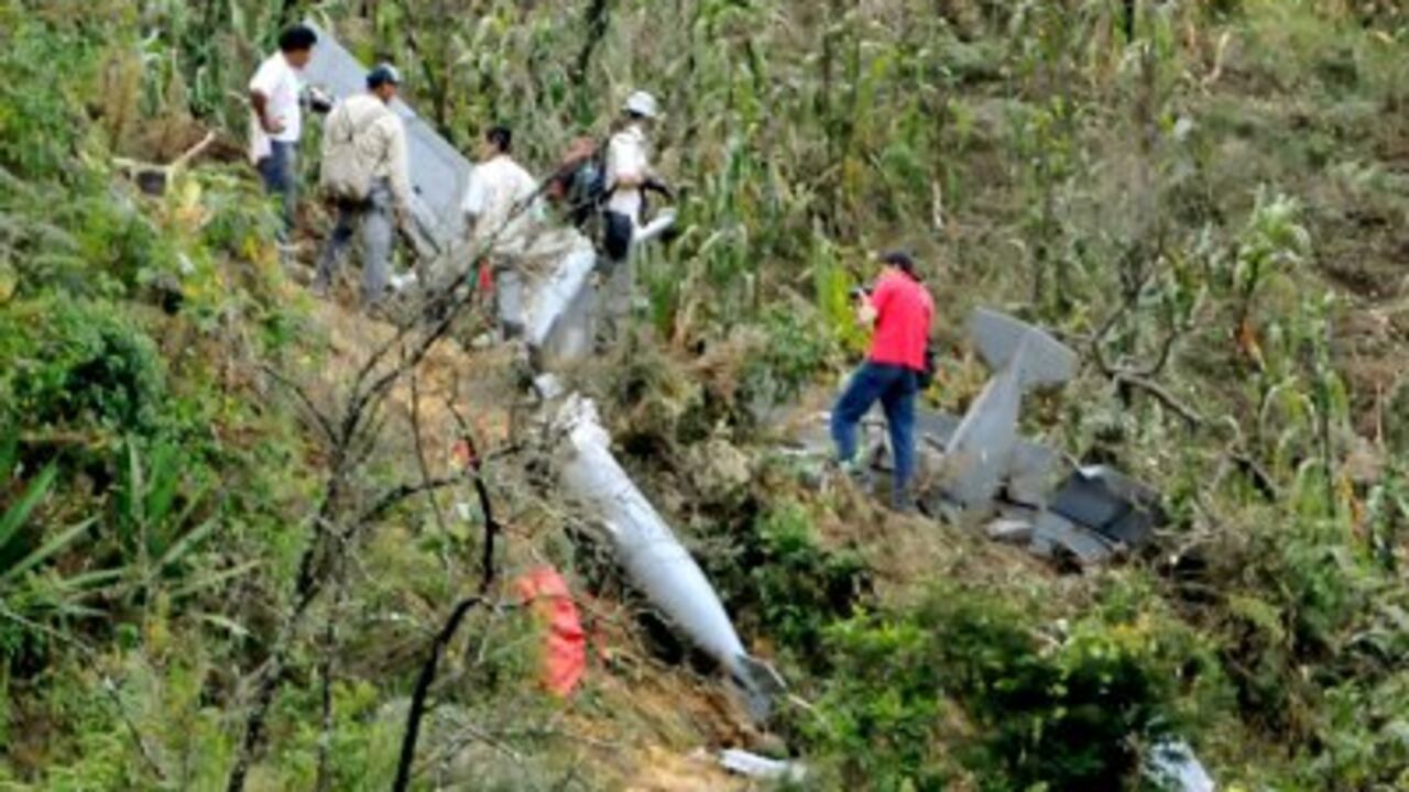 Miembros de la guardia indígena y periodistas observan los restos de un avión súper tucano de la Fuerza Aérea Colombiana.