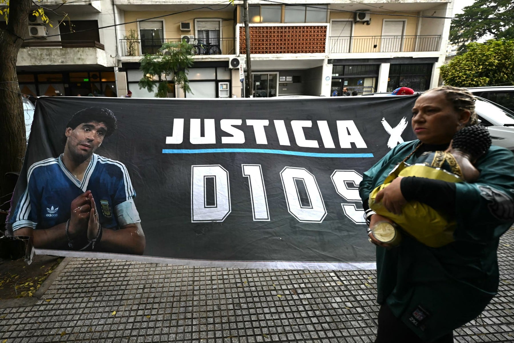 Una mujer pasa junto a una pancarta que muestra al legendario futbolista argentino Diego Maradona y exige justicia frente al tribunal antes de la audiencia sobre su muerte en San Isidro, provincia de Buenos Aires, Argentina, el 9 de junio de 2026.