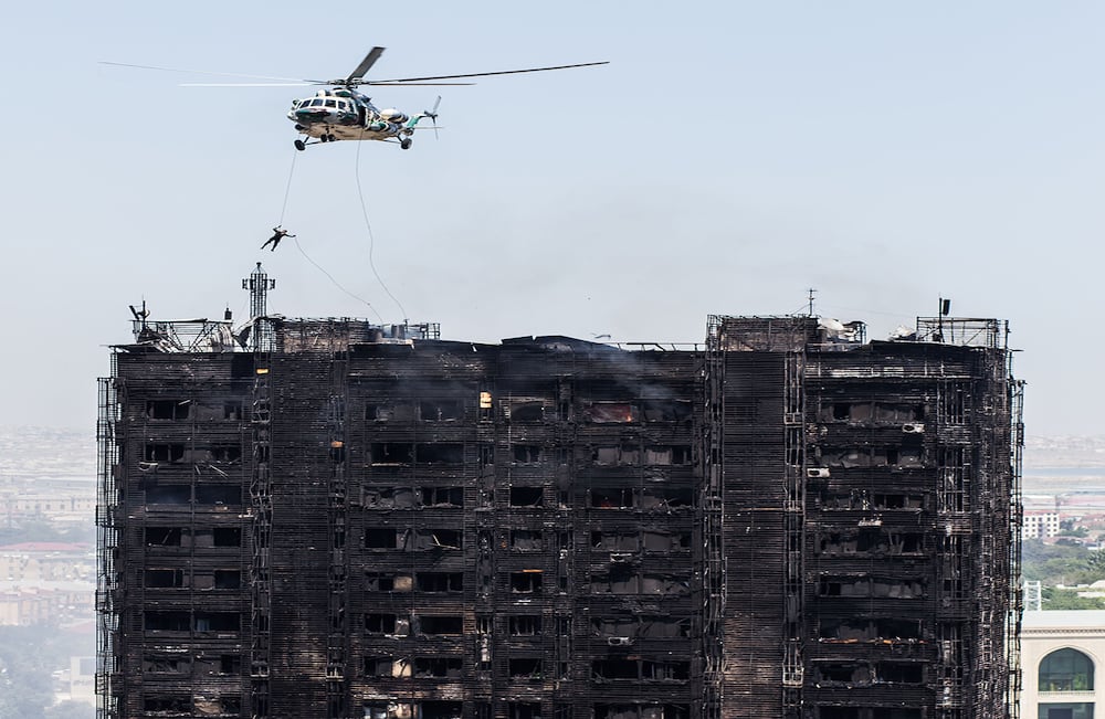Un rescatista alcanza el techo de un edificio incendiado que dejó 16 muertos y más de 50 heridos en Bakú, Azerbaiyán. (AP/Orxan Azim)