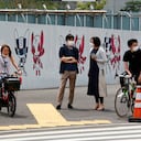 Personas se detienen en un esquina junto a un poster de promoción de los Juegos Olímpicos en Tokio el lunes 24 de mayo del 2021. (AP Photo/Koji Sasahara)