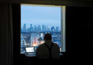 Man looking out of hotel window at Shinjuku business district