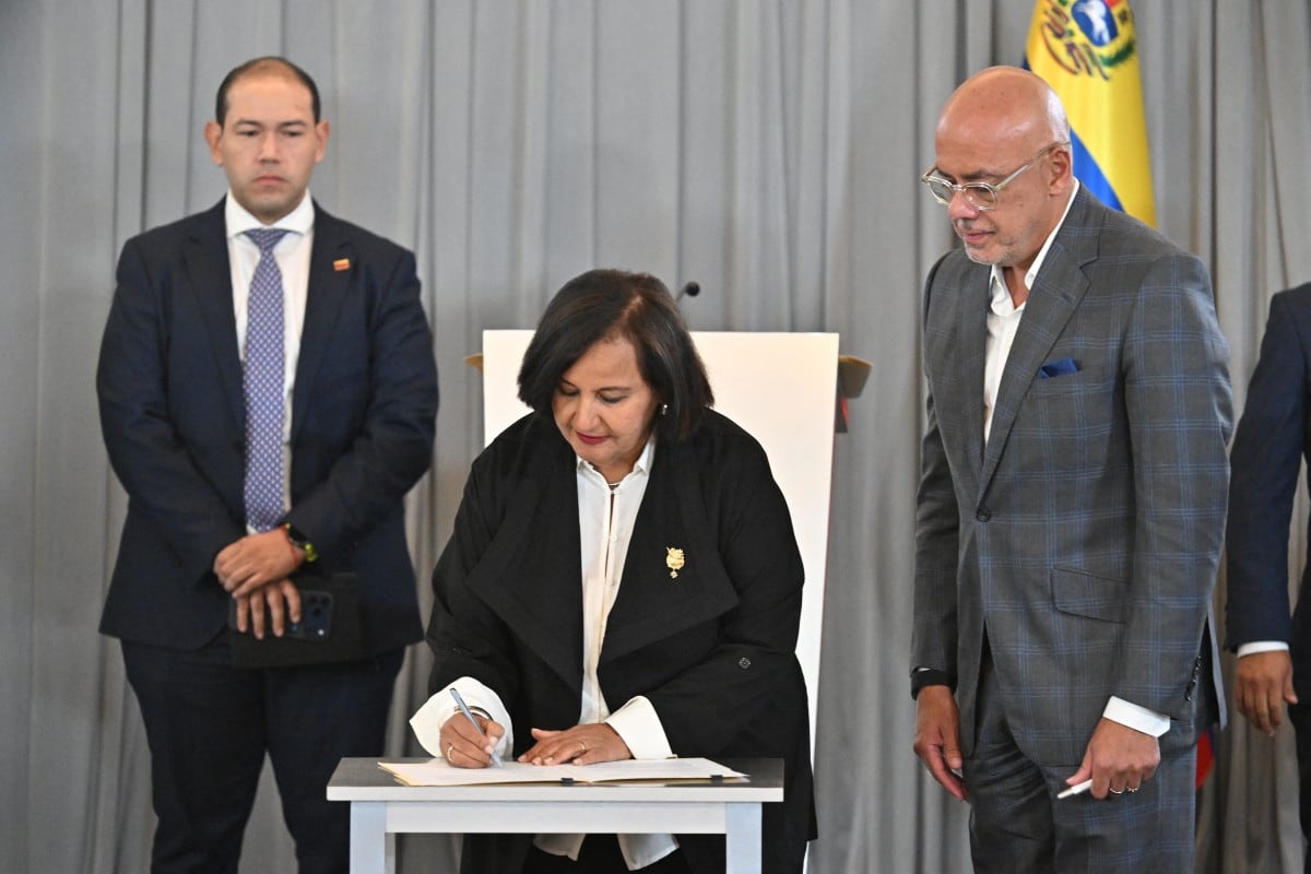 La representante de la oposición venezolana, Dinorah Figuera, firma un acuerdo junto al diputado Jorge Rodríguez.