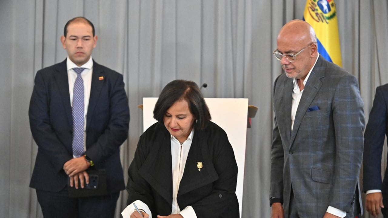 La representante de la oposición venezolana, Dinorah Figuera, firma un acuerdo junto al diputado Jorge Rodríguez.