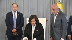 La representante de la oposición venezolana, Dinorah Figuera, firma un acuerdo junto al diputado Jorge Rodríguez.