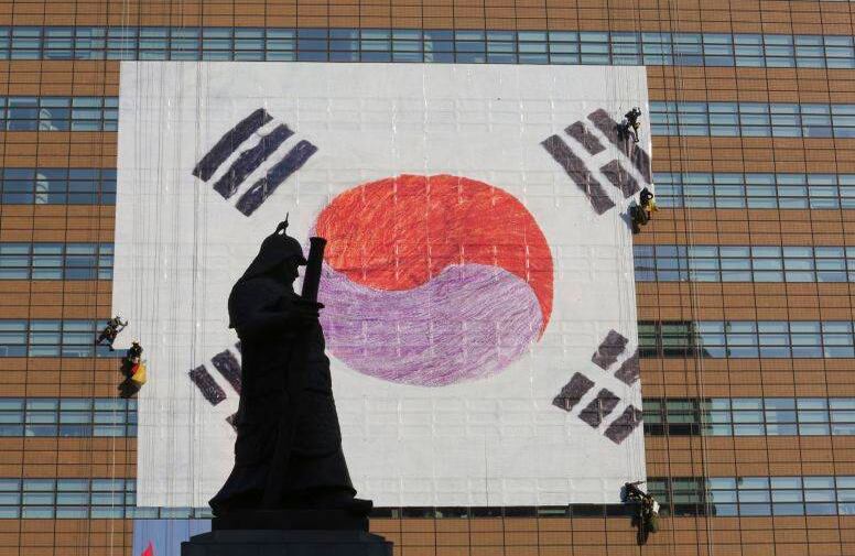 Trabajadores instalan una bandera nacional en un edificio en Seúl para la  ceremonia del gobierno con motivo del centenario del Día de Movimiento por la Independencia FOTO: Ahn Young-joon/AP