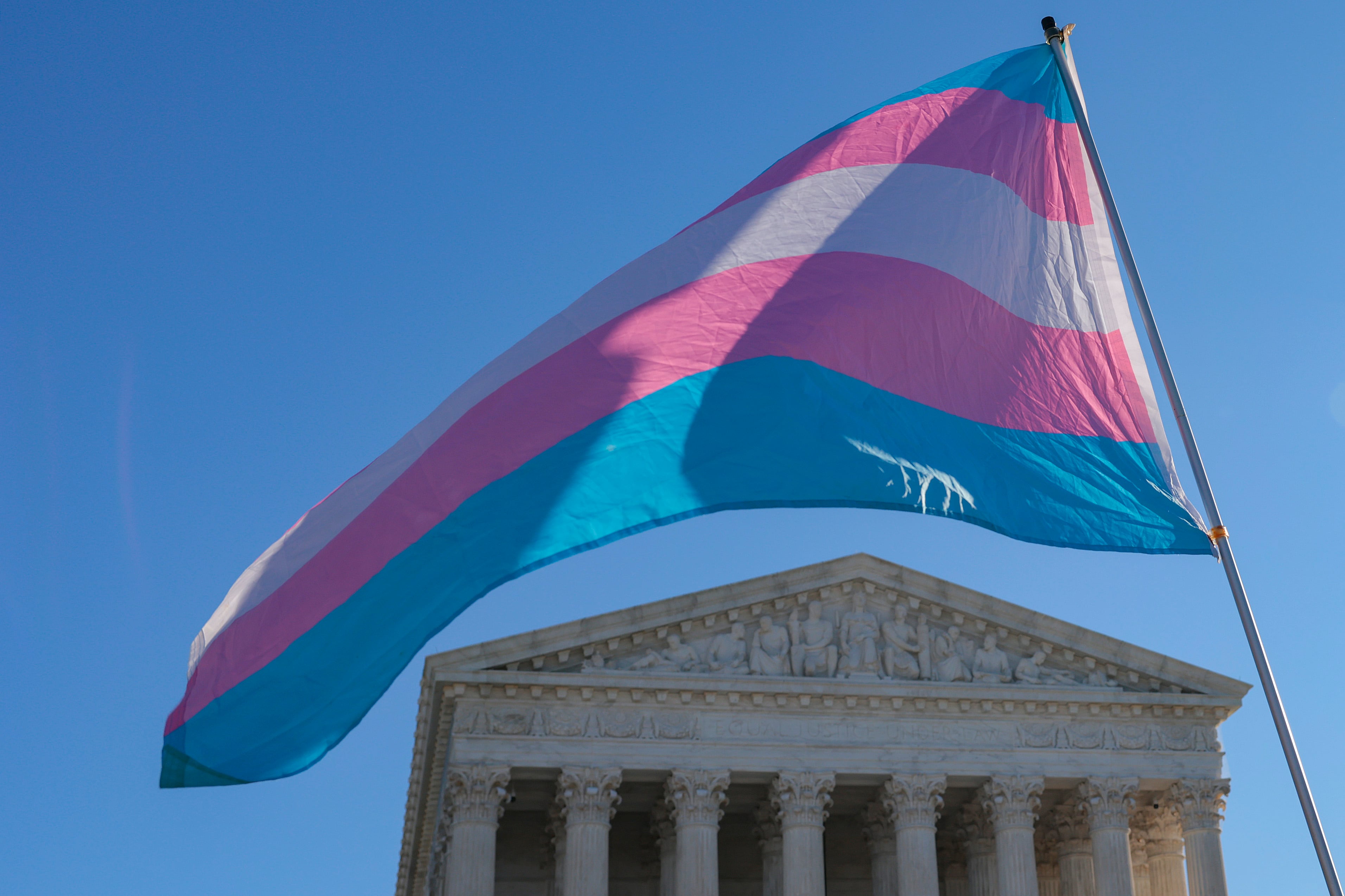 Manifestantes que apoyan a los atletas transgénero que compiten en deportes femeninos ondean una bandera del orgullo transgénero frente a la Corte Suprema el 13 de enero de 2026 en Washington, DC.