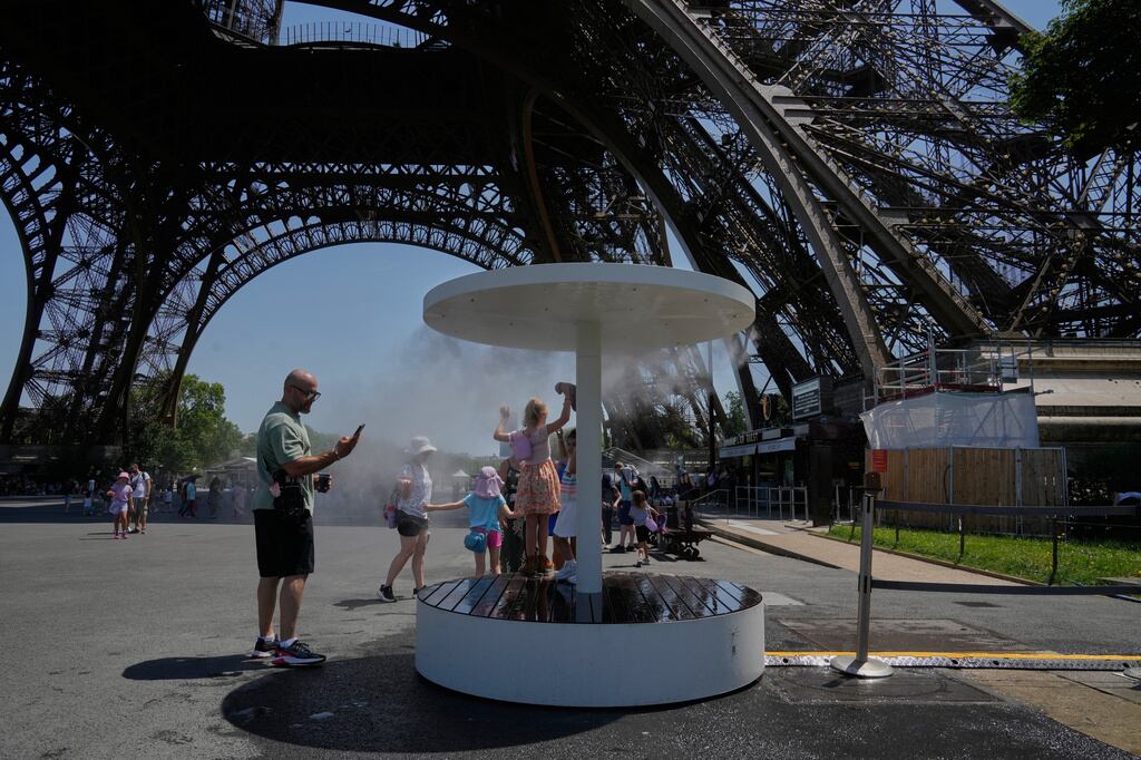 Unas personas se refrescan del fuerte calor en una fuente provisional colocada bajo la torre Eiffel en París.
