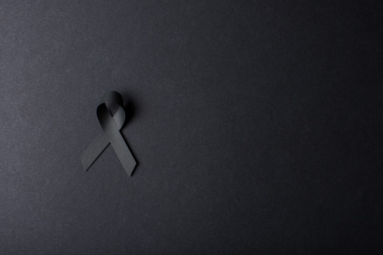 Black handmade awareness paper ribbon on black background.