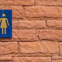 Toilet sign for woman on the red brick wall