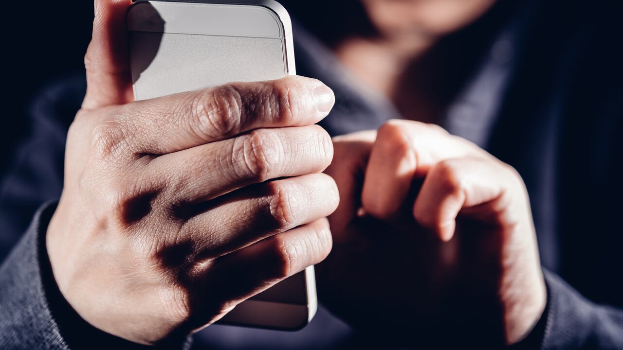 Hooded cyber crime hacker using mobile phone internet hacking in to cyberspace,online personal data security concept.