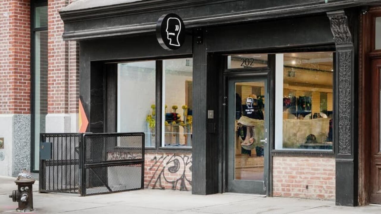 Exterior de la tienda Brain Dead en Nueva York mostrando productos de streetwear, decoración artística y una escultura central en un espacio moderno e industrial.