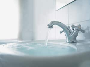 Cerca del lavabo del baño rebosante, lavamanos rebosado de agua, lleve abierta, grifo de agua, agua regandose.