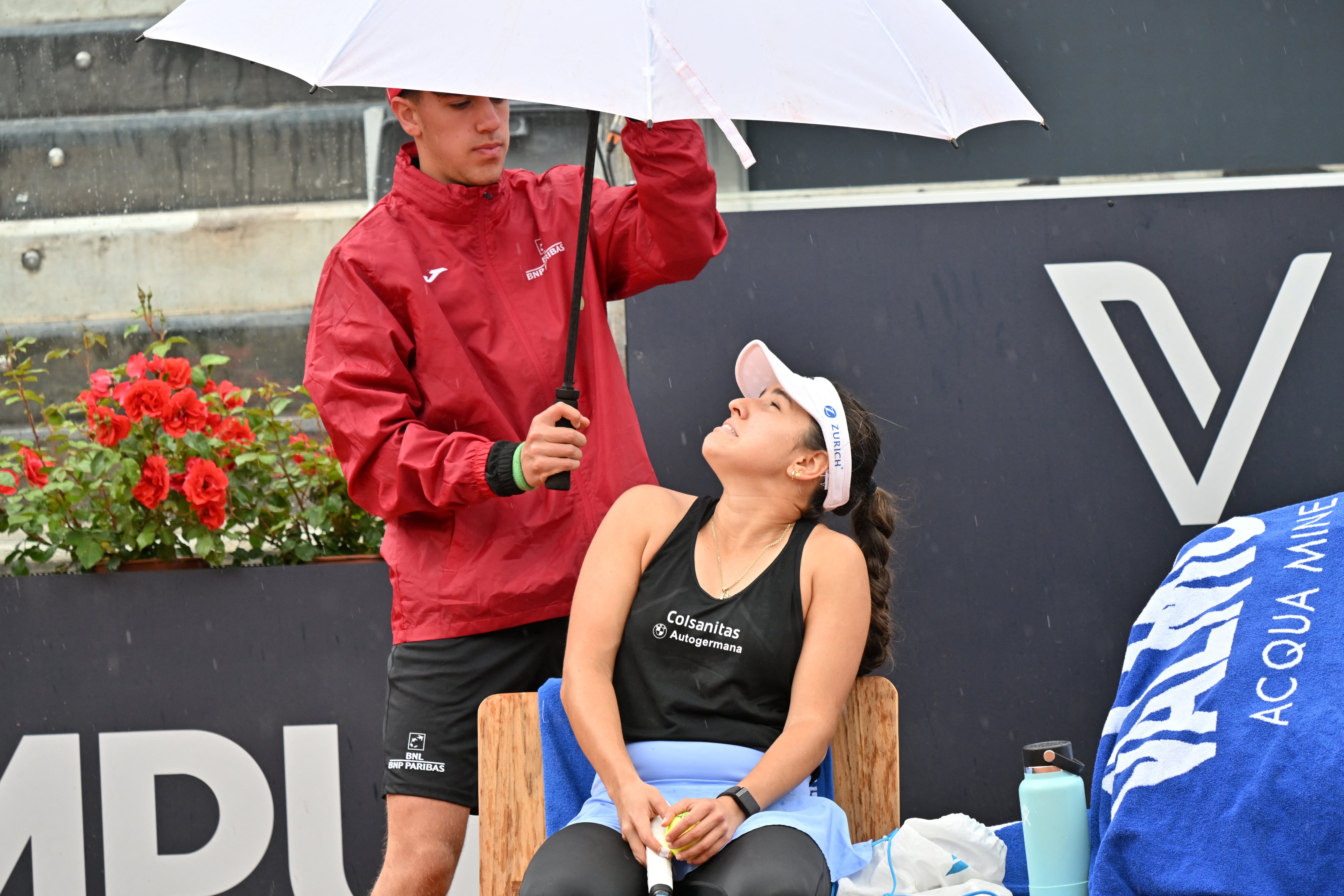 A ball boy protects Colombia's Maria Camila Osorio from the rain with an umbrella during her round of 32 match against France's Caroline Garcia at the Women's WTA Rome Open tennis tournament on May 13, 2023 at Foro Italico in Rome. (Photo by Filippo MONTEFORTE / AFP)