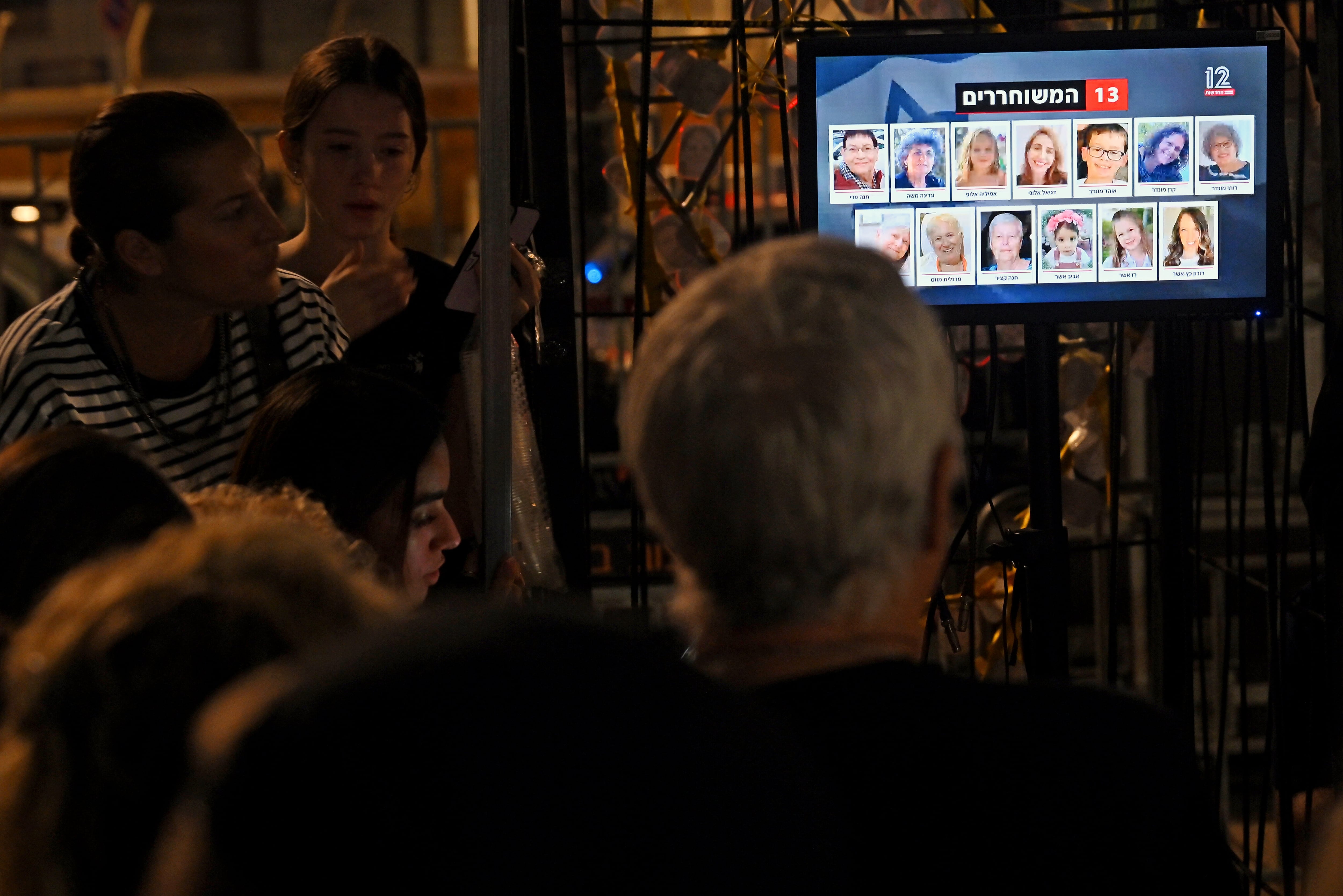 La gente ve las transmisiones de noticias mientras los rehenes son liberados en Egipto antes de ser llevados a Israel por el CICR, afuera del Museo de Tel Aviv el 24 de noviembre de 2023 en Tel Aviv, Israel. Esta mañana comenzó un alto el fuego de cuatro días entre Israel y Hamás, aunque las fuerzas israelíes permanecen en Gaza.