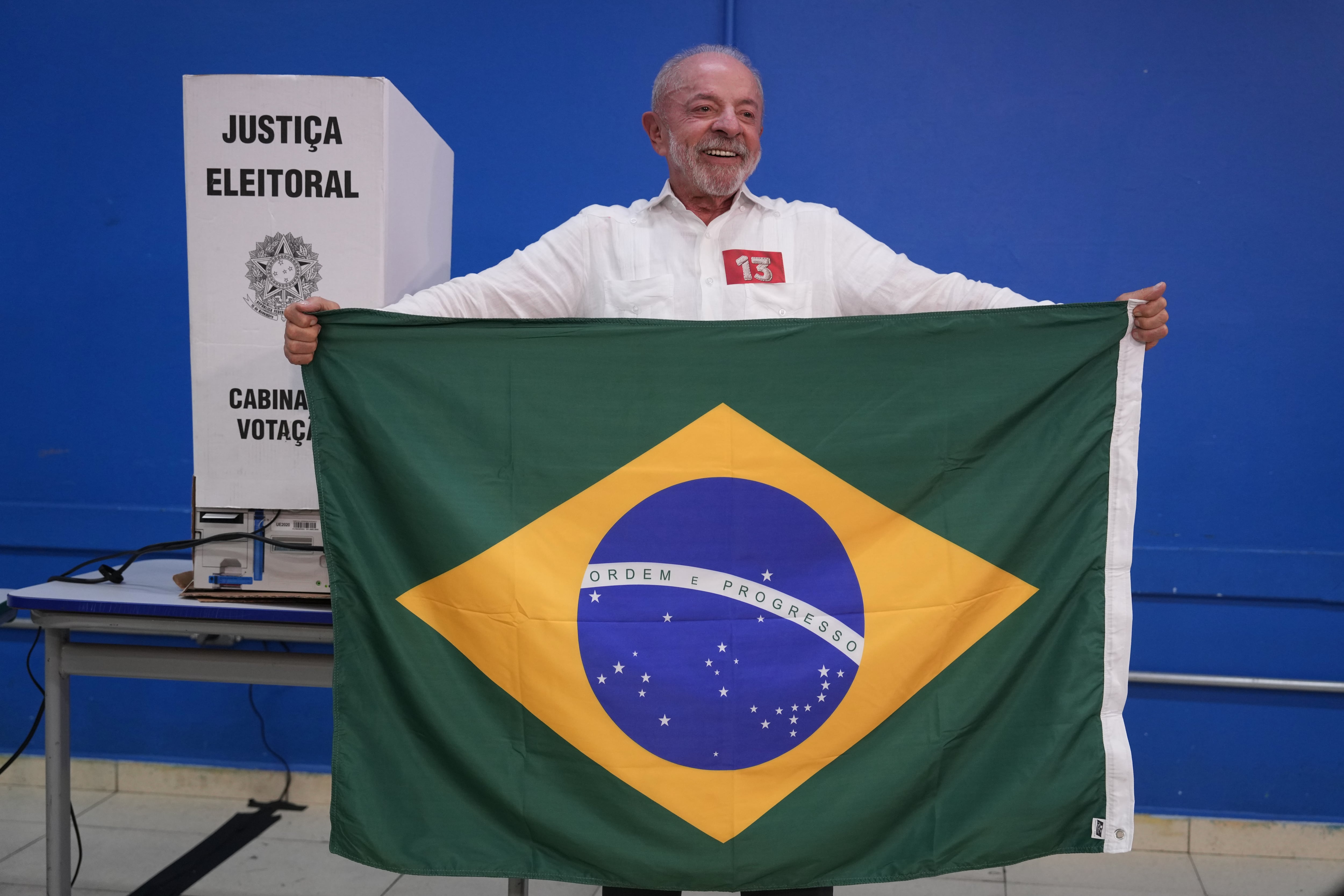 El presidente Luiz Inácio Lula da Silva, quien busca la reelección, exhibe una bandera de Brasil antes de votar en una segunda vuelta presidencial.