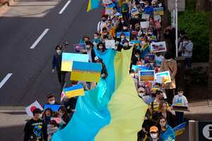 Los manifestantes sostienen una enorme bandera y pancartas durante una marcha que denuncia la invasión rusa de Ucrania en Tokio (AP Photo/Chisato Tanaka)