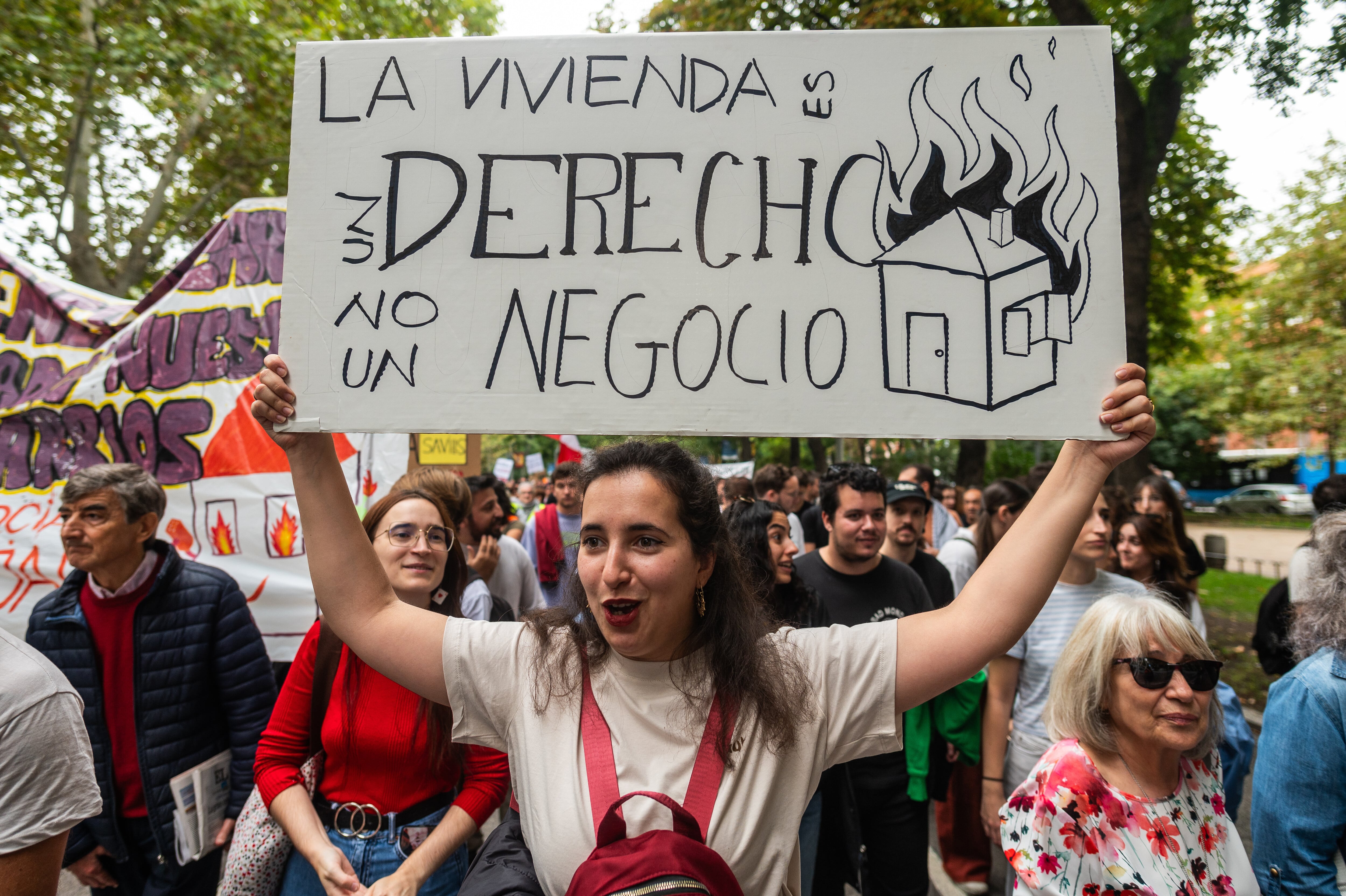 Una mujer portaba una pancarta con el lema "La vivienda es un derecho, no un negocio" durante una protesta.