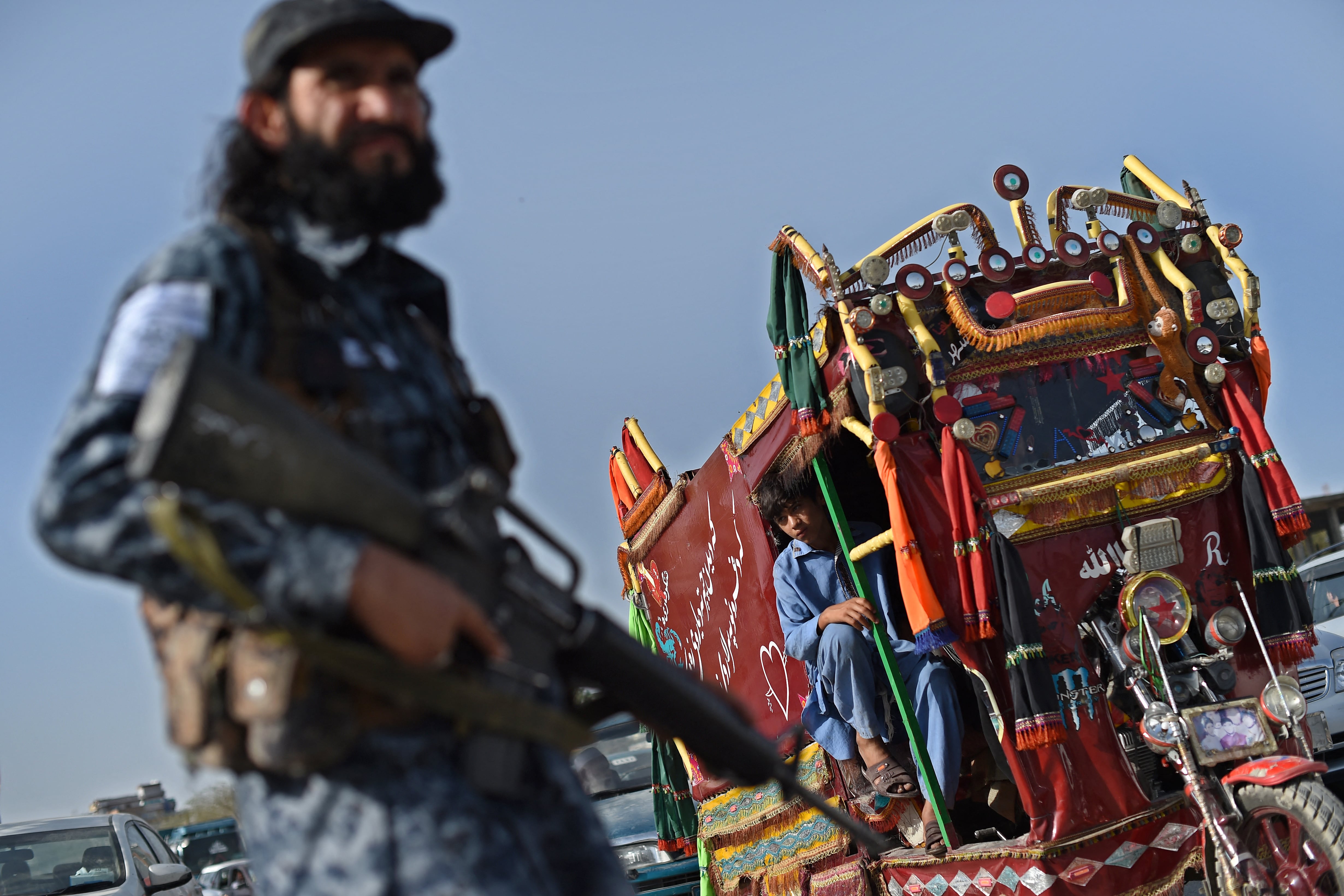 In this picture taken on October 3, 2021, a Taliban fighter working as part of a police force checks commuters at a road checkpoint in Kabul. - The Taliban's new police force already counts about 4,000 men in the capital, says a Kabul police spokesman, insisting the city is far safer than before, as the hardline group builds a police force from scratch. (Photo by WAKIL KOHSAR / AFP) / TO GO WITH Afghanistan-police-Taliban,FOCUS by Elise BLANCHARD