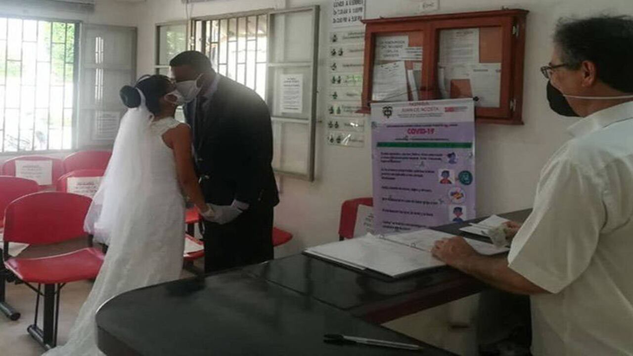 Elvia y Deimer se dan un beso a través de sus tapabocas, frente al notario de Juan de Acosta, en el Atlántico.