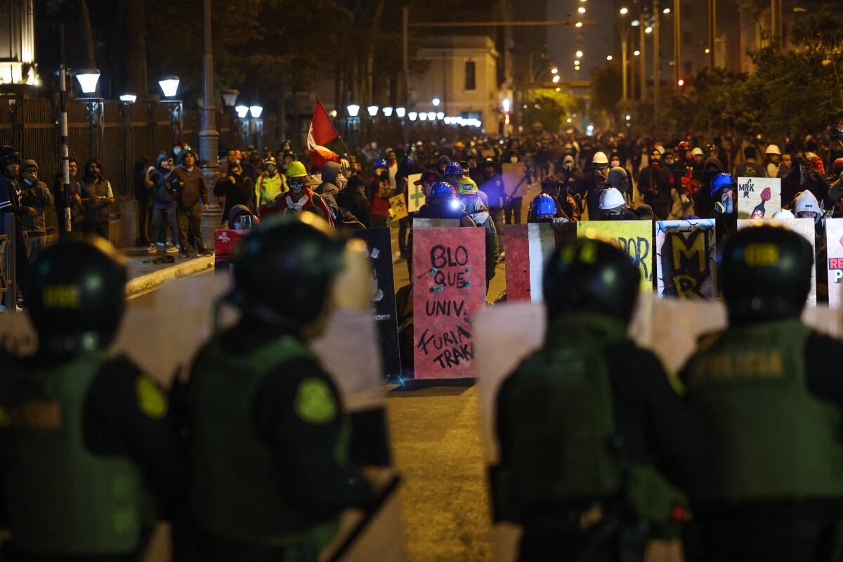 Agentes de la policía antidisturbios se protegen de los manifestantes durante una protesta contra el presidente interino de Perú, José Jeri, en Lima el 15 de octubre de 2025. (Foto de Hugo CUROTTO / AFP)