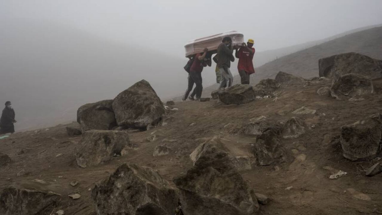 Los trabajadores del cementerio llevan el ataúd con el cadáver de Flavio Juárez, de 50 años, quien murió de covid-19 en el cementerio de Nueva Esperanza en las afueras de Lima, Perú, el martes 26 de mayo de 2020.