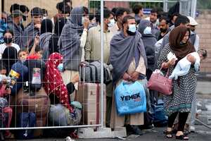 La gente se queda junto a una cerca en la base aérea de Ramstein U.S. en Ramstein, Alemania, lunes, 30 de agosto de 2021. La comunidad militar estadounidense más grande en el extranjero alberga miles de evacuados afganos en una ciudad de TENT en la barra aérea. (AP Foto / Matthias Schrader)