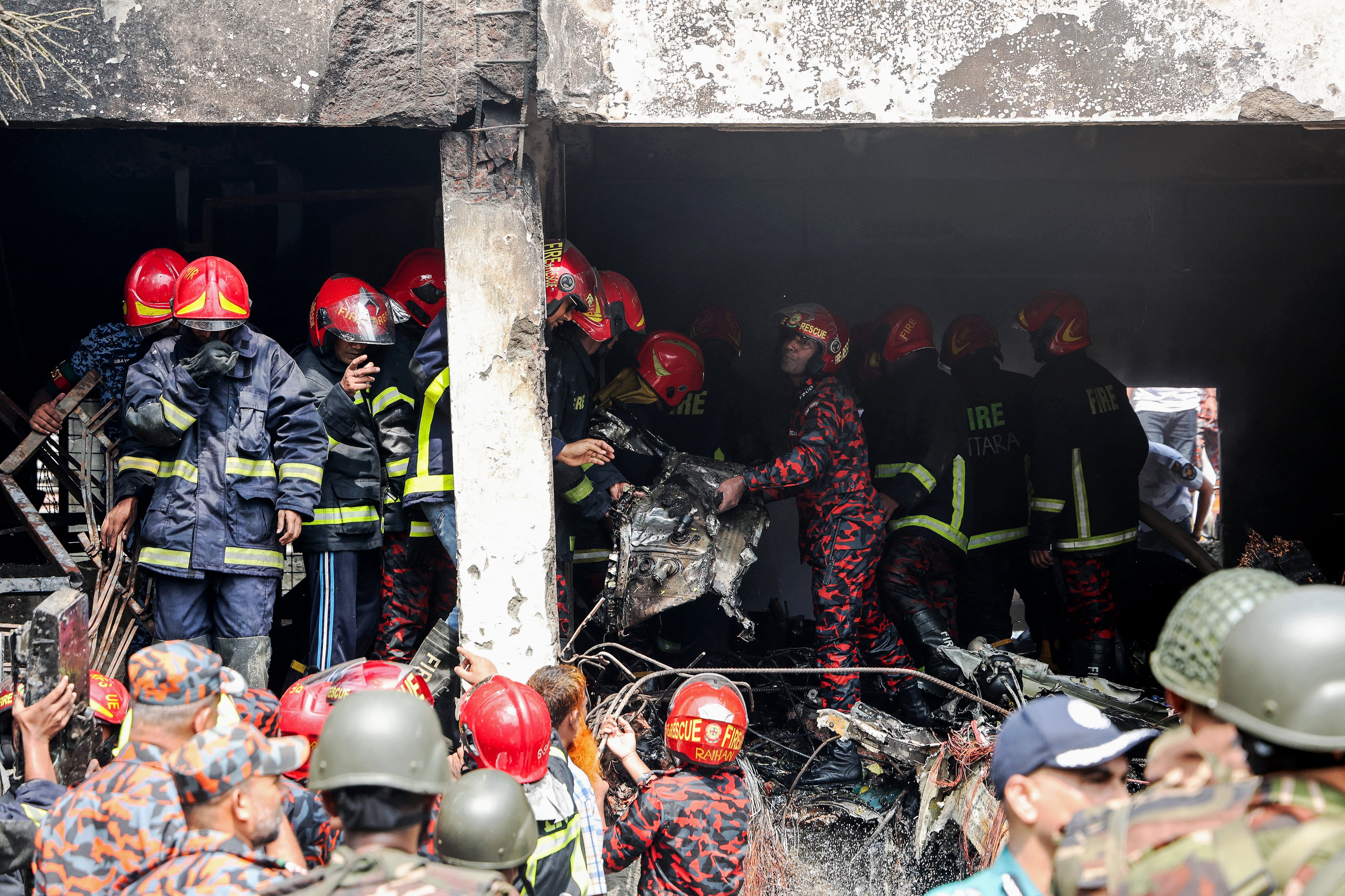 El servicio de bomberos y el personal de seguridad de Bangladesh llevan a cabo una operación de búsqueda y rescate mientras limpian los restos de un avión de entrenamiento de la Fuerza Aérea que se estrelló contra una escuela en Daca, el 21 de julio de 2025