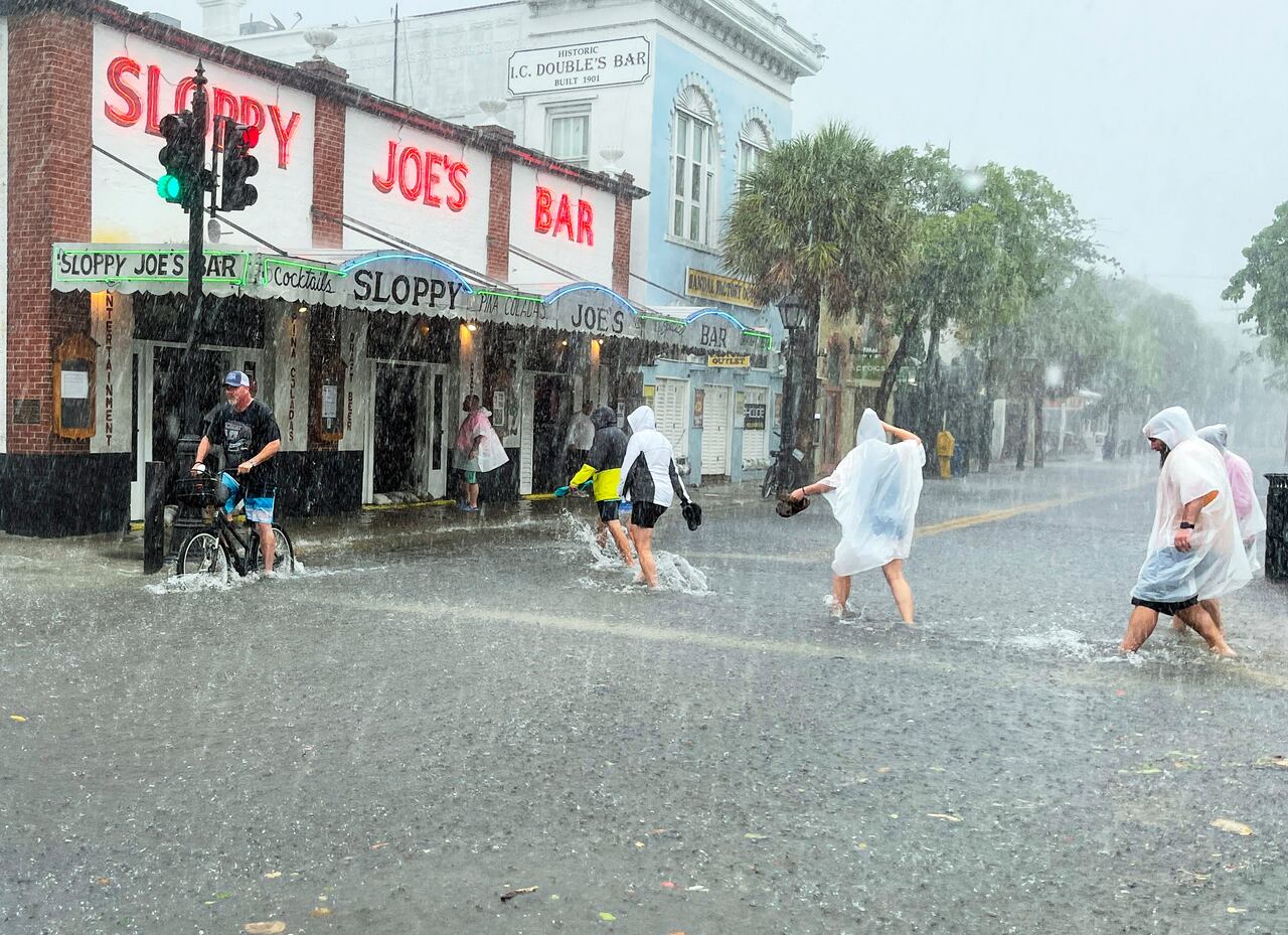 Los visitantes decididos se dirigen al Sloppy Joe's Bar mientras cruzan una calle Duval inundada mientras fuertes vientos y lluvia pasan sobre Key West, Florida, el martes 6 de julio de 2021. (Rob O'Neal / The Key West Citizen vía AP)