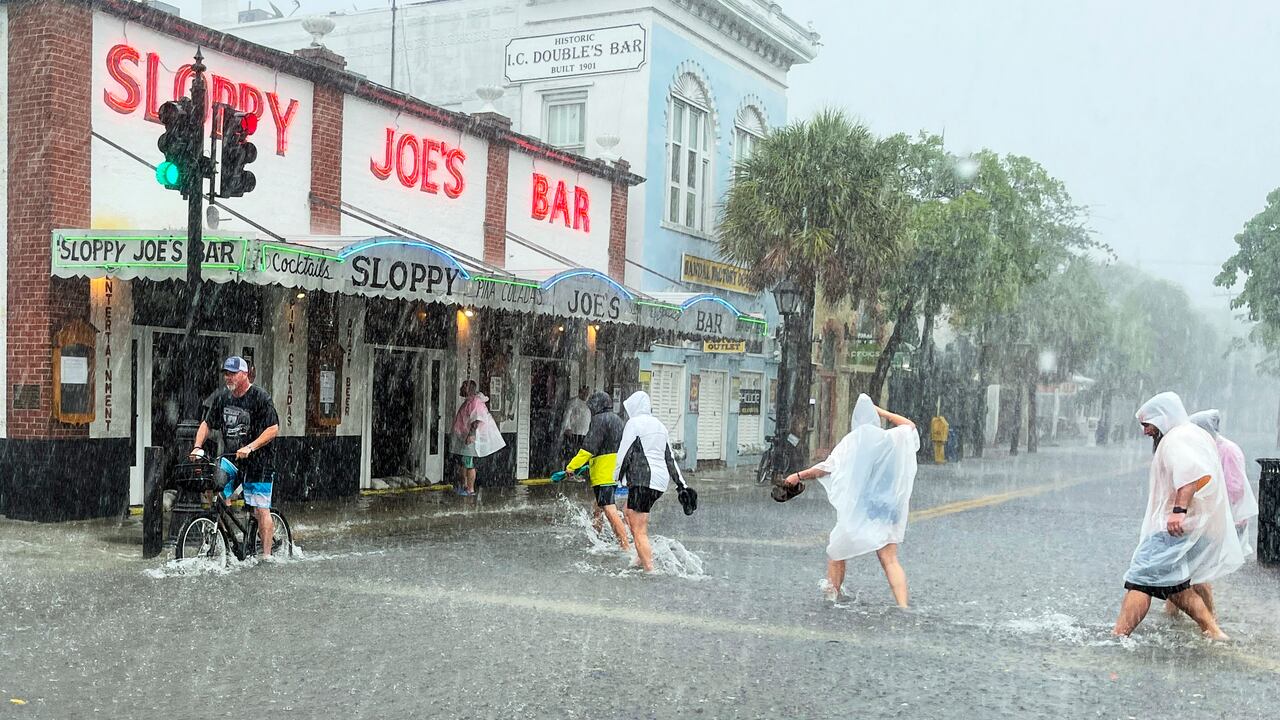 Los visitantes decididos se dirigen al Sloppy Joe's Bar mientras cruzan una calle Duval inundada mientras fuertes vientos y lluvia pasan sobre Key West, Florida, el martes 6 de julio de 2021. (Rob O'Neal / The Key West Citizen vía AP)