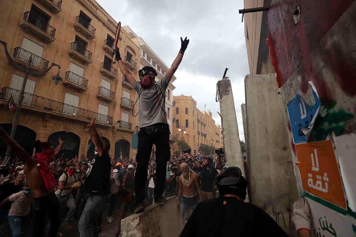 Los manifestantes celebran después de quitar una losa de hormigón de una barrera para abrir la vía que conduce al edificio del parlamento. AP Photo/Hassan Ammar.