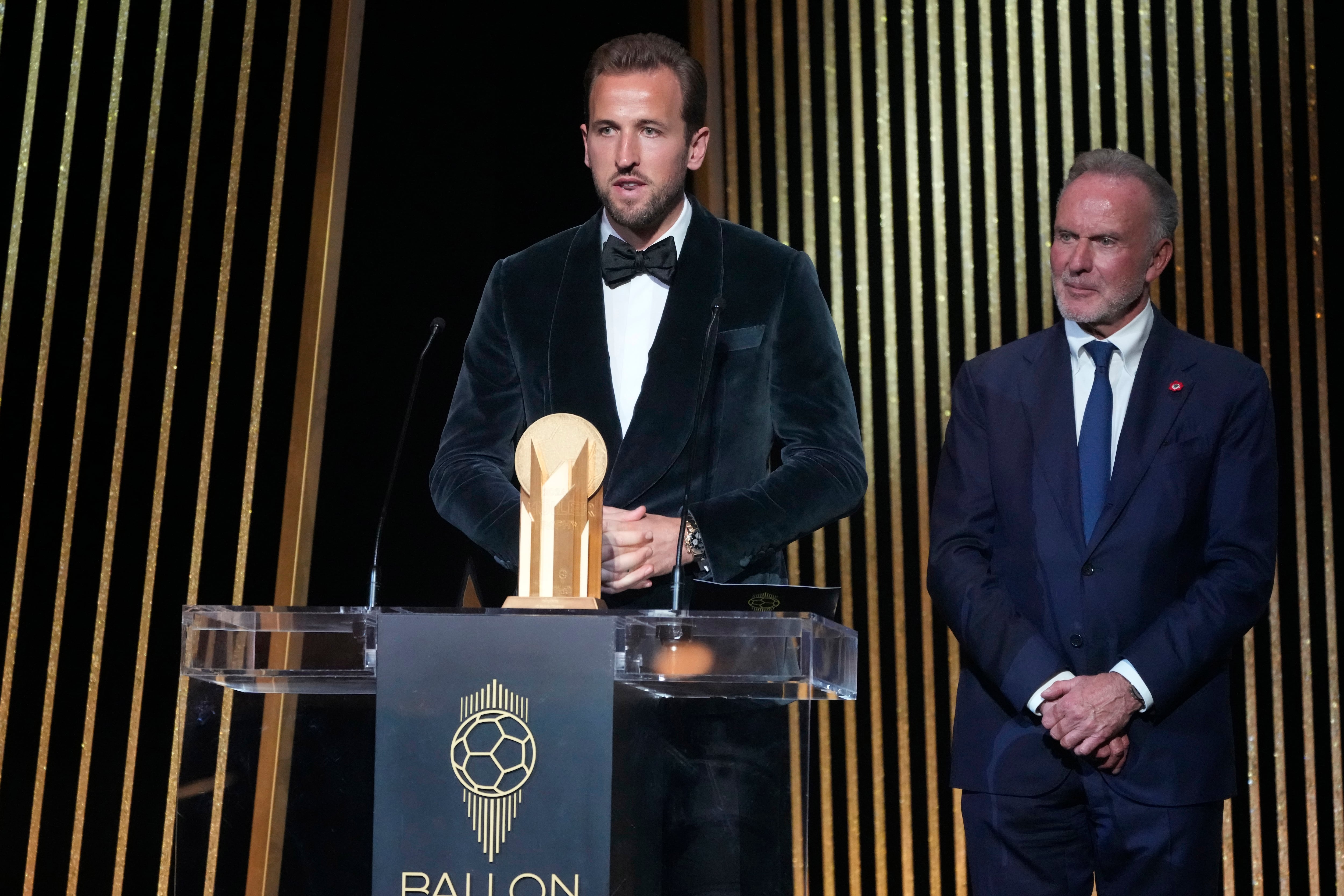 England's player Harry Kane, left, is flanked by former German player Karl-Heinz Rummenigge as he receives the Gerd Mueller trophy during the 68th Ballon d'Or (Golden Ball) award ceremony at Theatre du Chatelet in Paris, Monday, Oct. 28, 2024. (AP Photo/Michel Euler)